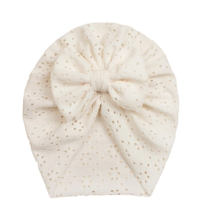 Detail of white hollow embroidered baby turban with large bow showing breathable mesh fabric