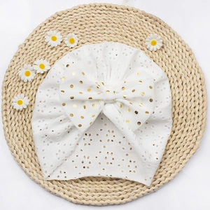 Detail eines weißen Baby-Turban-Huts mit großer goldener Polka-Dot-Schleife