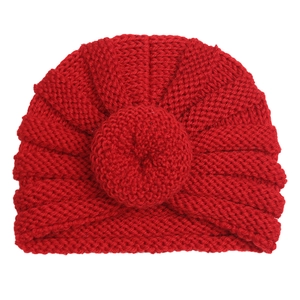 Close-up detail of red knit baby donut hat featuring a textured round decorative knot