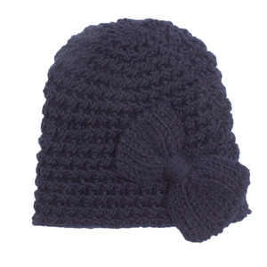 Détail macro du tricot épais et du grand nœud sur ce bonnet bleu marine bébé