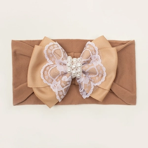 Détail du bandeau bébé avec un grand nœud en dentelle et des perles blanches élégantes