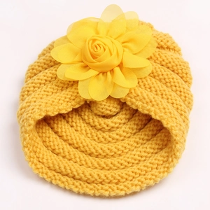 Détail du bonnet en tricot jaune pour bébé montrant la texture et la grande rose