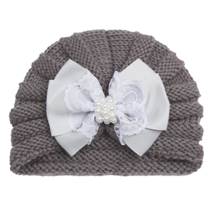 Détail du turban gris tricoté pour bébé avec grand nœud en dentelle blanche et perles