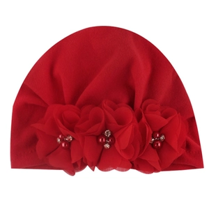 Detailed view of red baby turban hat with chiffon flowers, pearls and rhinestones