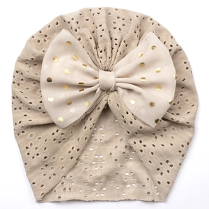 Detail der Baby-Turban-Mütze mit hohlem Strickmuster und goldener Punktschleife