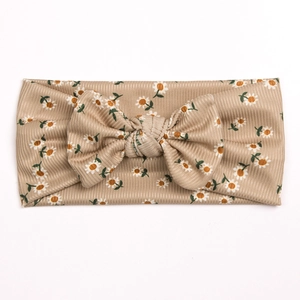 Detail of baby headband featuring soft ribbed beige fabric with daisy floral prints