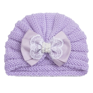 Détail du bonnet en tricot lavande pour bébé avec gros nœud et perles élégantes