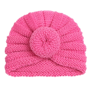 Macro detail of bright pink knit baby turban hat with soft ribbed wool texture and top knot