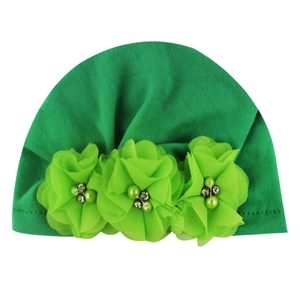 Detail of green baby turban hat featuring three tulle flowers with pearls and rhinestones
