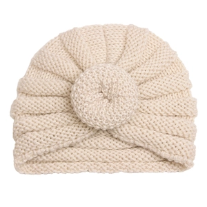 Detailed knit texture of a warm cream baby donut hat with a round woven knot detail