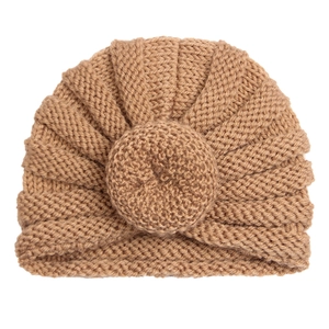 Detail of camel knit baby turban hat with radial texture and a donut knot on white background