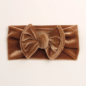 Détail de la texture d'un bandeau bébé en velours caramel avec un grand nœud décoratif