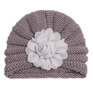 Détail du bonnet tricoté lilas pour bébé avec une fleur en mousseline grise en relief