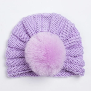 Détail du bonnet en tricot violet clair pour bébé avec un grand pompon en fausse fourrure