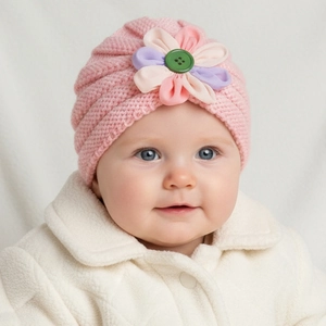 Close-up of baby pink knit turban hat with multicolored fabric flowers and green button