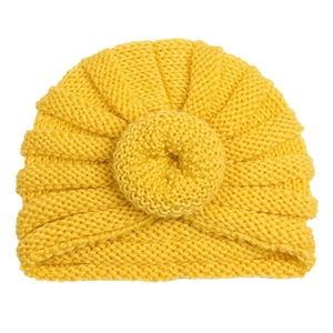 Detailed view of yellow knitted baby turban hat with circular donut knot on white background