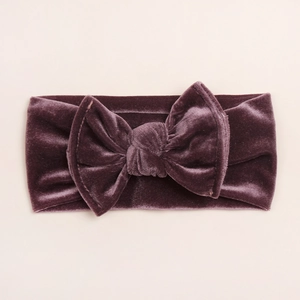 Détail d'un bandeau pour bébé en velours violet avec un grand nœud fait à la main