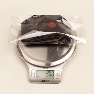 Detail view of baby flower beanie in packaging on scale weighing 30.0 grams