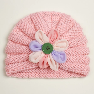Detail of pink knitted baby hat with multi-color chiffon flower and green button accent