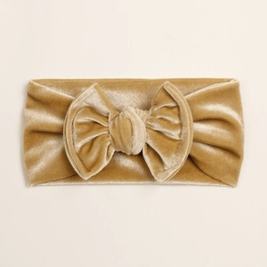 Détail d'un bandeau pour bébé en velours doré doux avec un nœud et une texture peluche