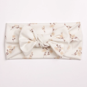 Detailed close-up of ivory ribbed knit baby headband with yellow floral print and a bow