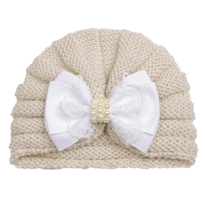 Close-up of baby knit turban hat with lace bow and pearl details in cream white