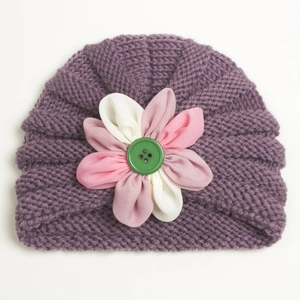 Macro detail of purple knit baby turban with colorful layered flower and green button