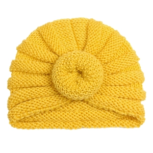 Bright yellow knitted baby turban hat with donut knot decoration on white background