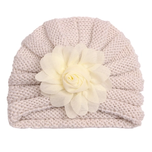 Détail du bonnet en tricot crème pour bébé orné d'une grande fleur en tissu multicouche