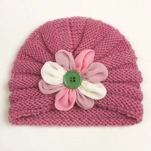 Close-up of pink knit baby hat featuring 3D chiffon flower and a green button detail