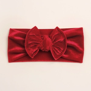 Détail d'un bandeau en velours rouge pour bébé avec un grand nœud fait à la main