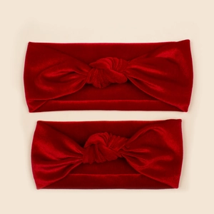 Detail of red velvet knotted headbands for mothers and babies on beige background