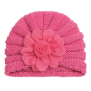 Détail du bonnet en tricot rose pour bébé avec décoration de fleur en mousseline