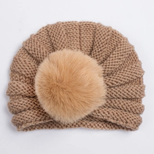 Détail du bonnet turban tricoté pour bébé en marron avec grand pompon en fourrure