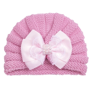 Close-up of pink knit baby turban featuring satin bow with lace and pearl details