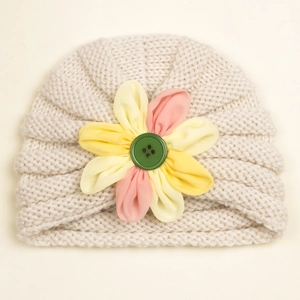 Detailed knit texture of cream baby turban hat with a large floral button accent