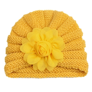 Détail du bonnet en tricot jaune pour bébé avec une grande fleur et une texture épaisse
