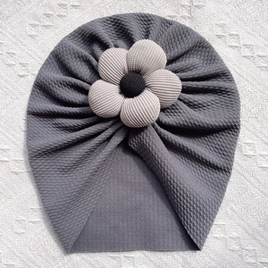Detailed waffle knit texture of dark grey baby turban hat with a large 3D fabric flower