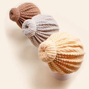 Close-up of baby turban hats with waffle knit texture and donut knot in neutral colors