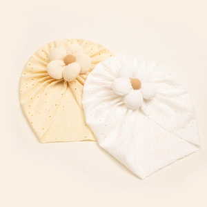 Detail of baby hollow-out floral beanies in soft yellow and white breathable fabric