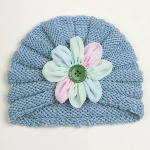 Close-up of blue knit baby hat with three-color fabric flower and green button detail