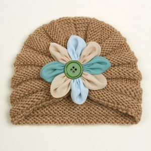 Detail of warm baby knit turban hat featuring a decorative 3D fabric flower with button