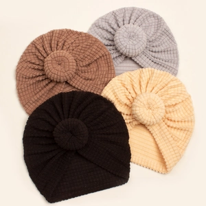 Flat lay of four textured waffle knit baby turban hats with stylish donut knot details