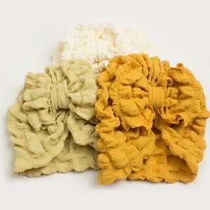 Three-piece baby turban set in cream, olive, and yellow textured fabric with big bows