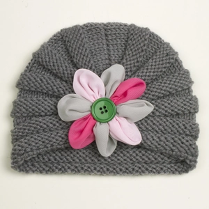 Detail of grey knitted baby hat showing ribbed texture and pink fabric flower with green button