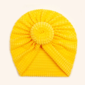 Detail of bright yellow baby donut hat with ribbed texture and round top knot