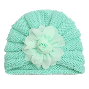 Détail de la maille et fleur en mousseline vert menthe sur un bonnet pour bébé