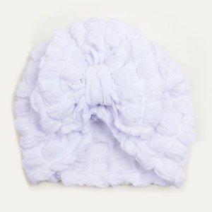 Detail shot of white baby turban hat featuring bubble texture fabric and large bow