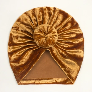 Close-up of golden velvet baby hat with a thick 3D donut knot and soft ribbed texture