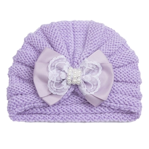 Detail of purple infant knit hat featuring large satin bow with lace and pearl accents